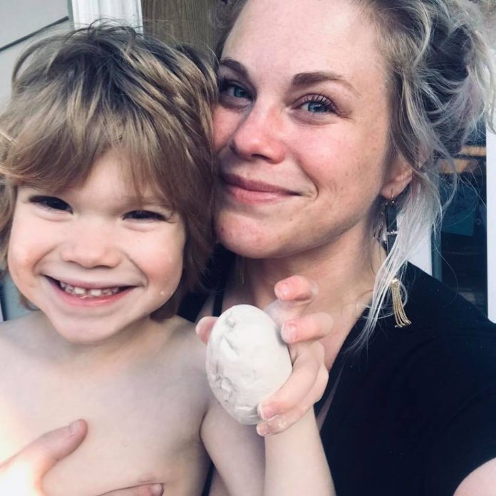 A portrait shows Ashley Hurlburt holding her daughter and smiling at the camera.