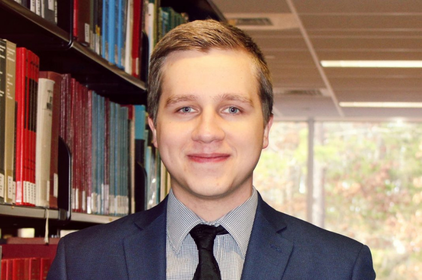 A close-up shows a man wearing a suit and tie.