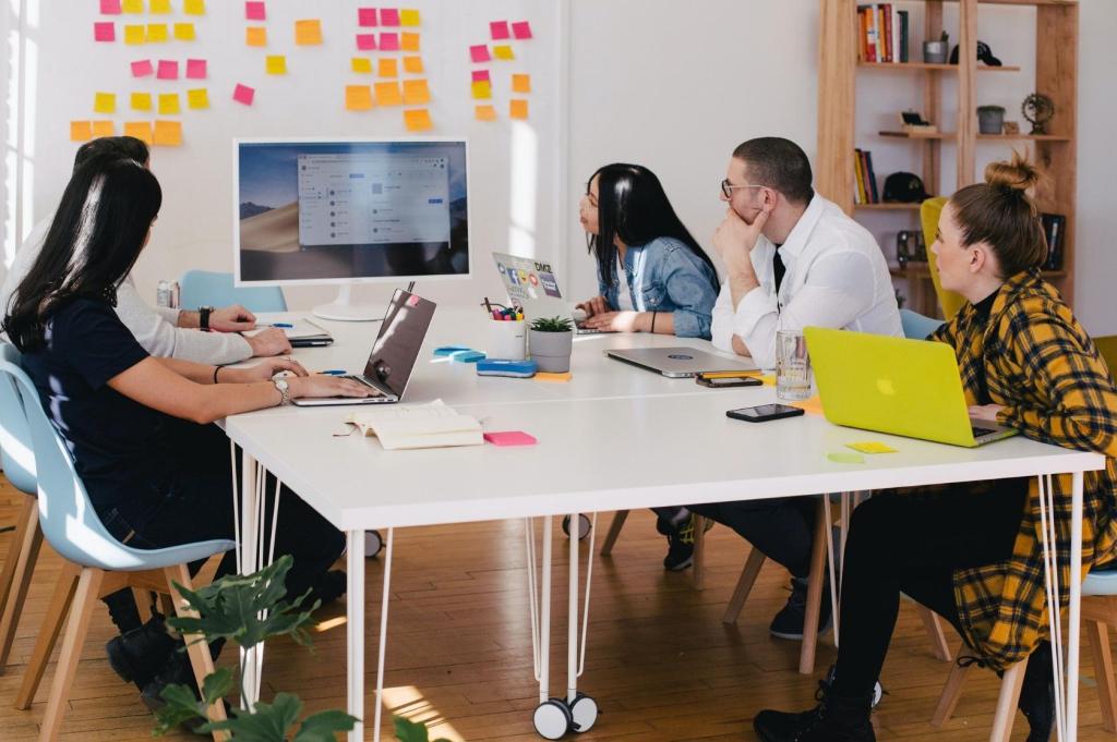 Teams sits around a desk looking at a computer.