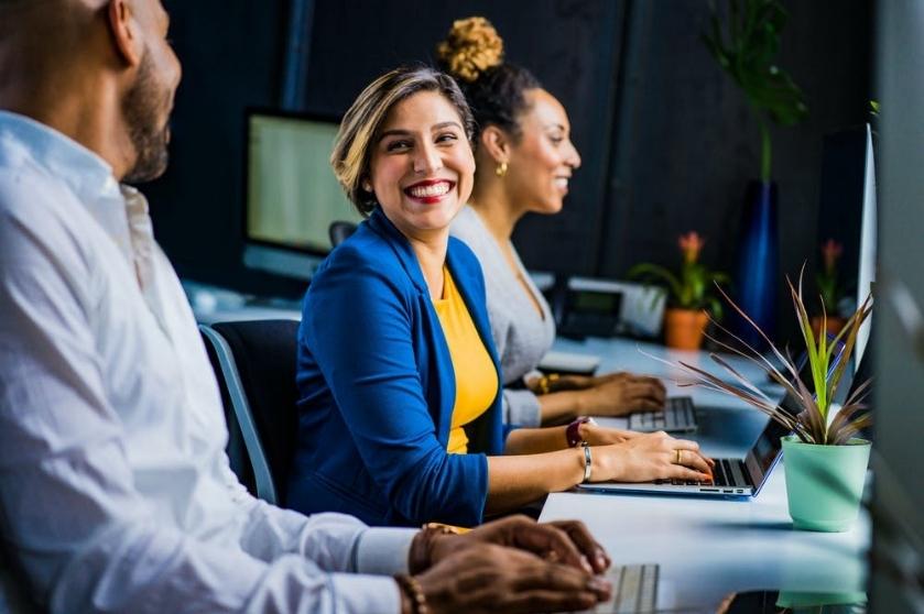 Two coworkers smile at each other.