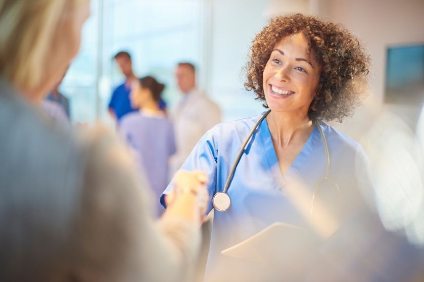 Woman doctor handing something to another with doctors in the background