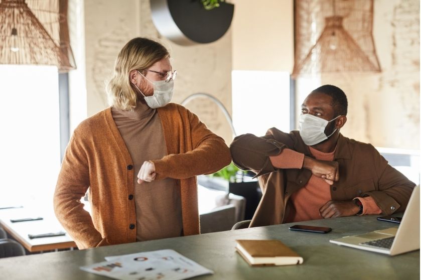 two men in masks elbowing each other for a high five gesture