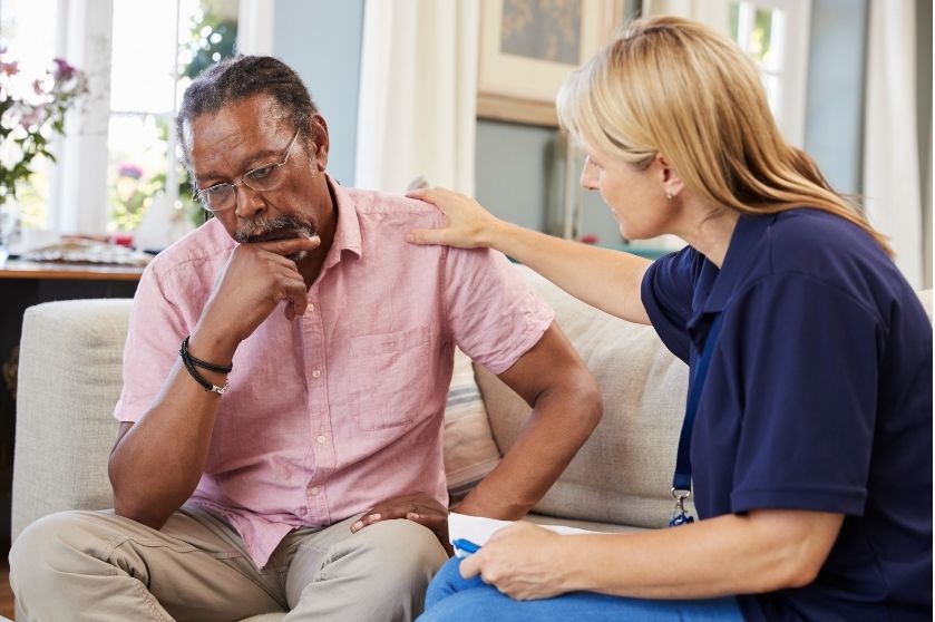 female social worker with hand on older man's shoulder