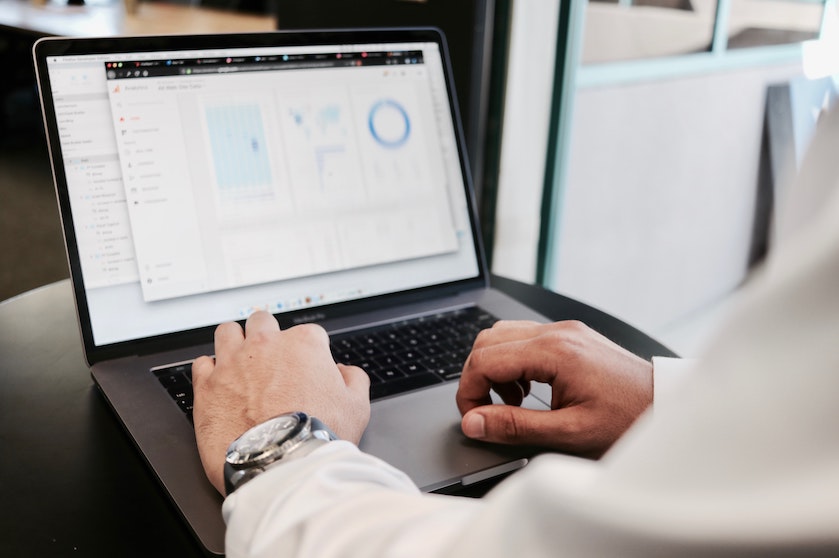 A man in a dress shirt sits at a laptop.